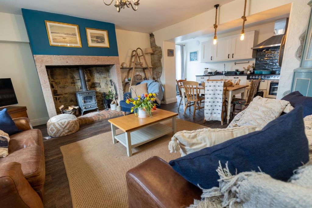 a living room with a couch and a fireplace at Rose Cottage by Coast & Country Stays in Beadnell