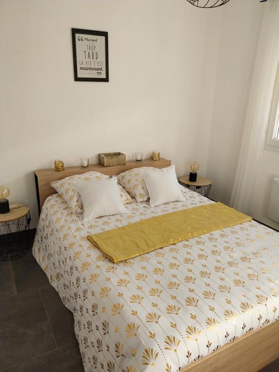 a bedroom with a bed with a yellow comforter at Location en nuitée in Abeilhan