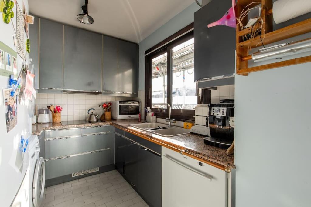 a kitchen with gray cabinets and a sink at 120 Grenelle - Spacieux Duplex avec vue sur la tour Eiffel in Paris