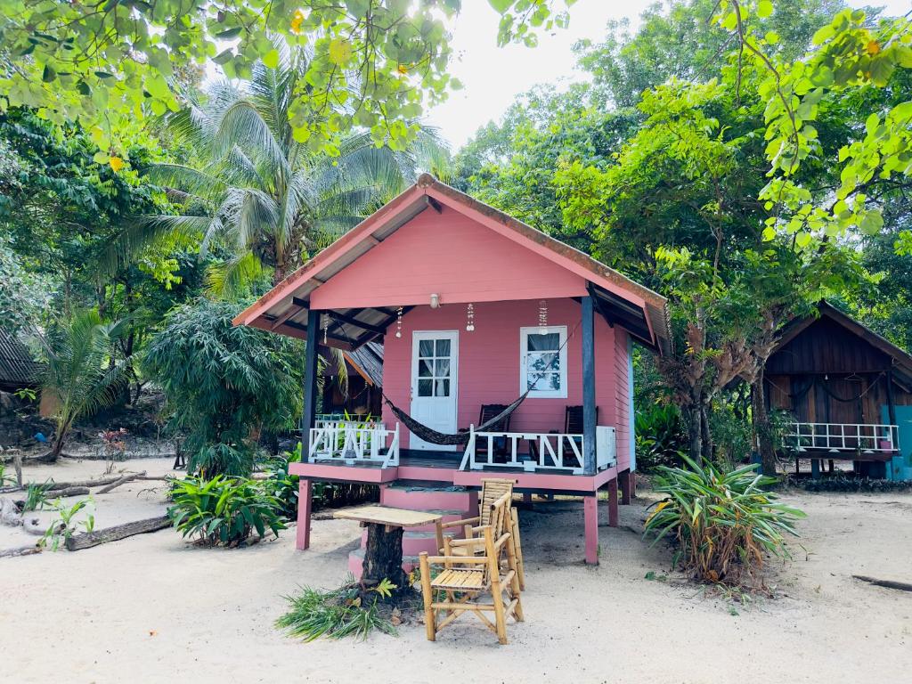 a small pink house on the beach with a table and chairs at Full Moon Bungalow Resort Koh Chang Ranong in Koh Chang Ranong