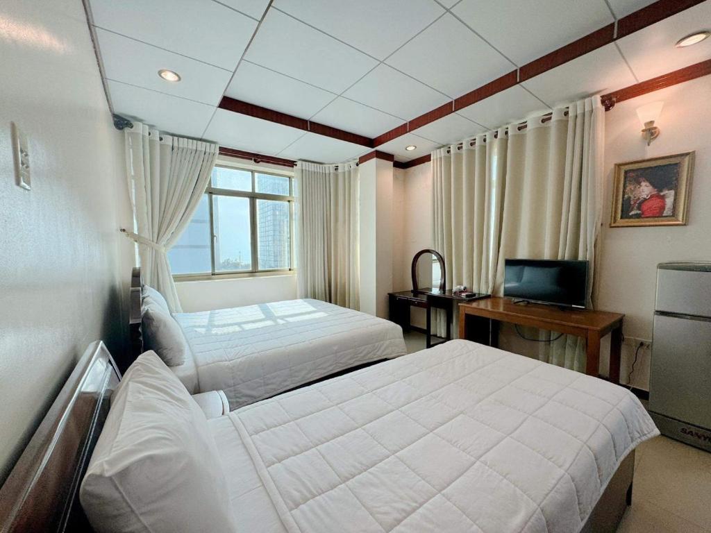 a bedroom with two beds and a desk and a television at Phúc Đạt Hotel in Vung Tau