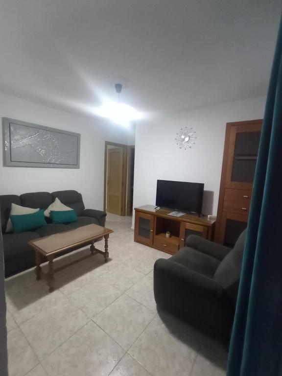 ein Wohnzimmer mit einem Sofa und einem TV in der Unterkunft Apartamento La Reina Home in Córdoba