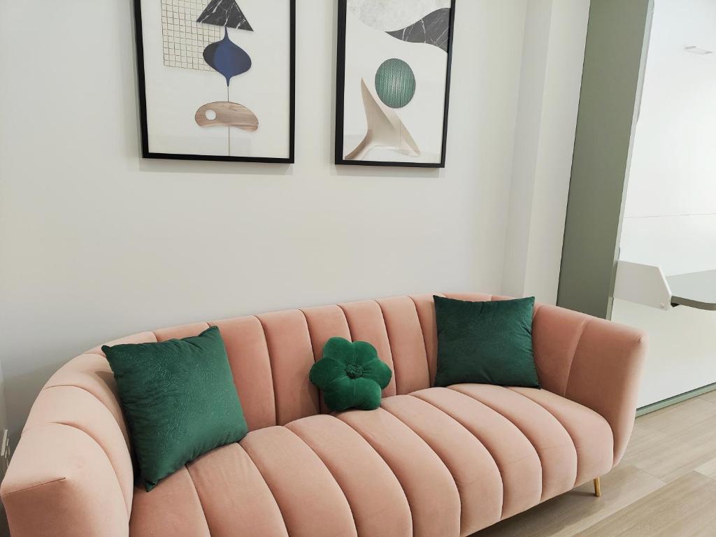 ein rosafarbenes Sofa mit grünen Kissen im Wohnzimmer in der Unterkunft Apartamentos Centro Oviedo Caveda in Oviedo