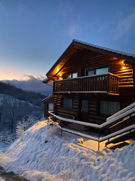 a log cabin in the snow with lights on at Bellevue Chalet in Râşnov