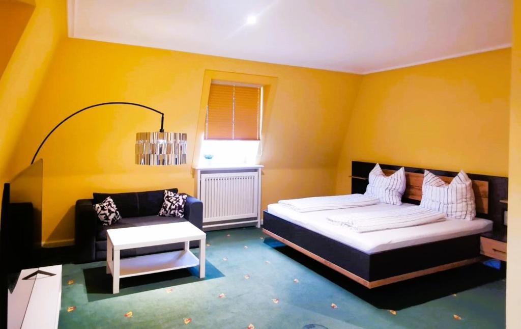 gelbes Zimmer mit einem Bett und einem Sofa in der Unterkunft Schöne Mindeltal Wohnung - Legoland - Skylinepark in Thannhausen