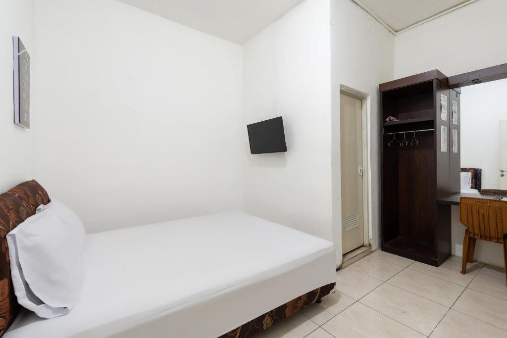 ein weißes Bett in einem Zimmer mit einem Tisch in der Unterkunft OYO Life 2108 Griya Aisyah Residence in Surabaya