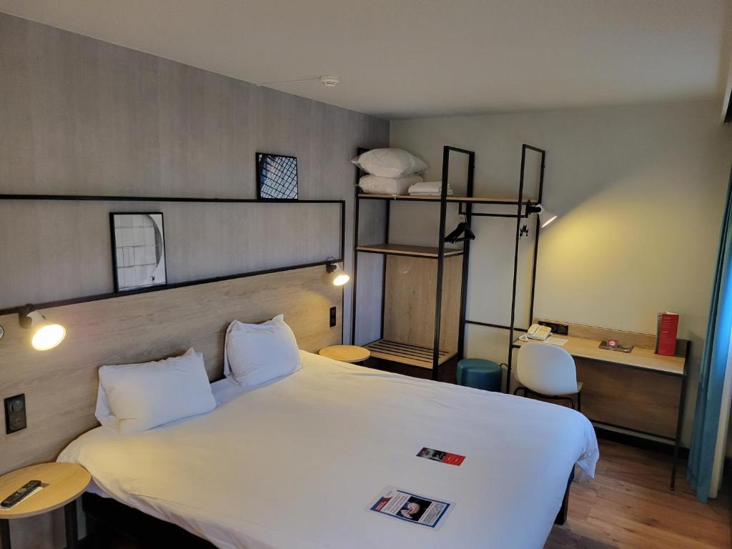 a bedroom with a large white bed and a desk at ibis Chateauroux in Châteauroux