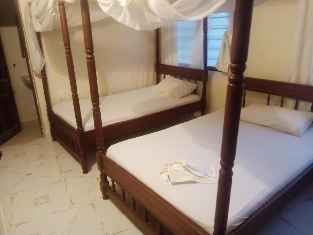 two bunk beds in a room with white sheets at Seafront House in Lamu