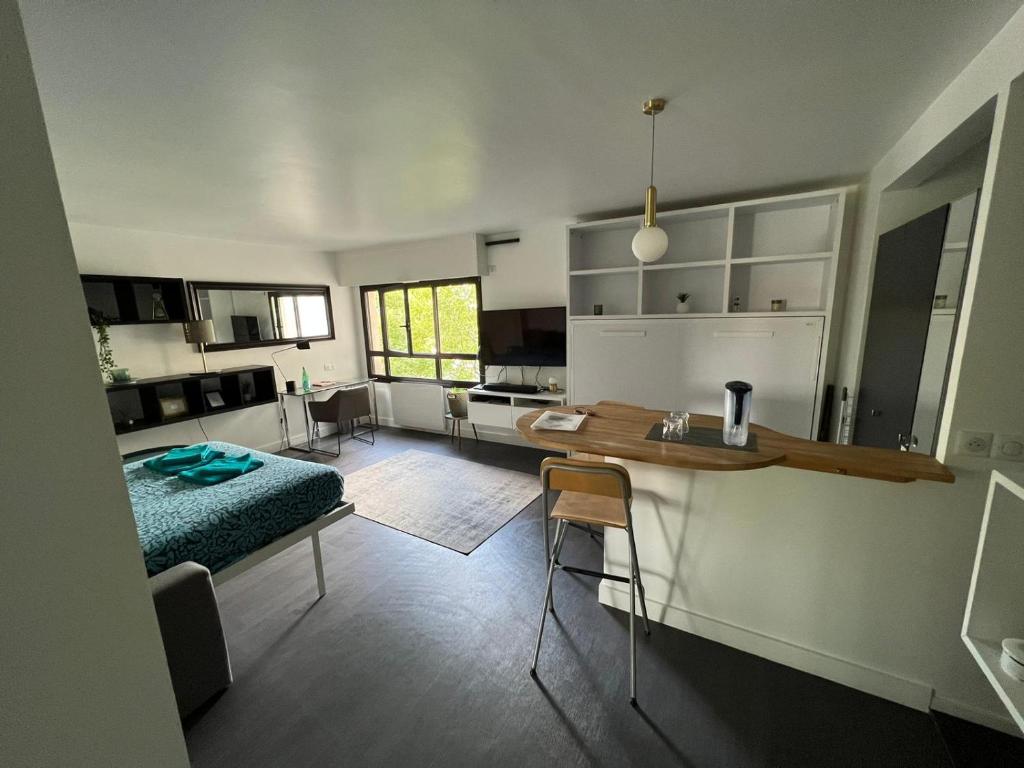 eine Küche und ein Wohnzimmer mit einem Tisch und einem Bett in der Unterkunft Appartement calme à Bercy non loin de l'Accor Aréna in Paris