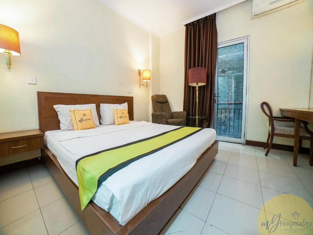 ein Schlafzimmer mit einem großen Bett mit einem Stuhl und einem Fenster in der Unterkunft Excellent Seven Hotel by My Hospitality in Bandung
