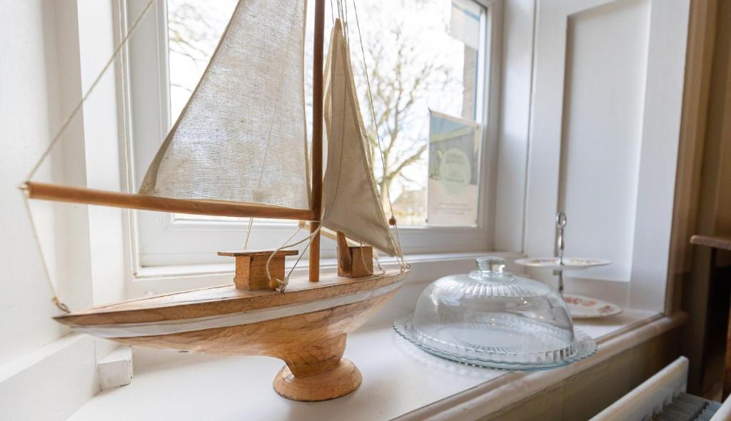 a wooden model boat sitting on a window sill at Church Cottage in Beadnell