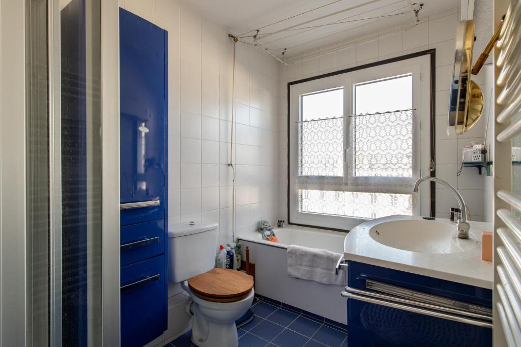 a bathroom with a toilet and a sink and a window at 120 Grenelle - Spacieux Duplex avec vue sur la tour Eiffel in Paris