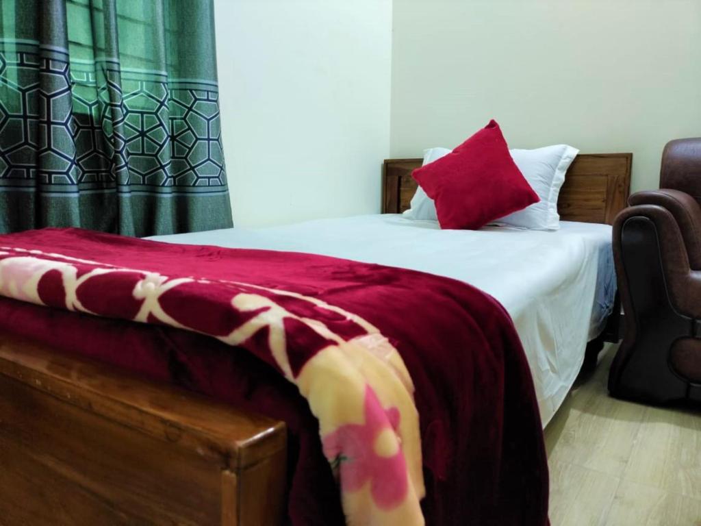 um quarto com uma cama com um cobertor vermelho em New Hotel Shapno Nibash em Dhaka