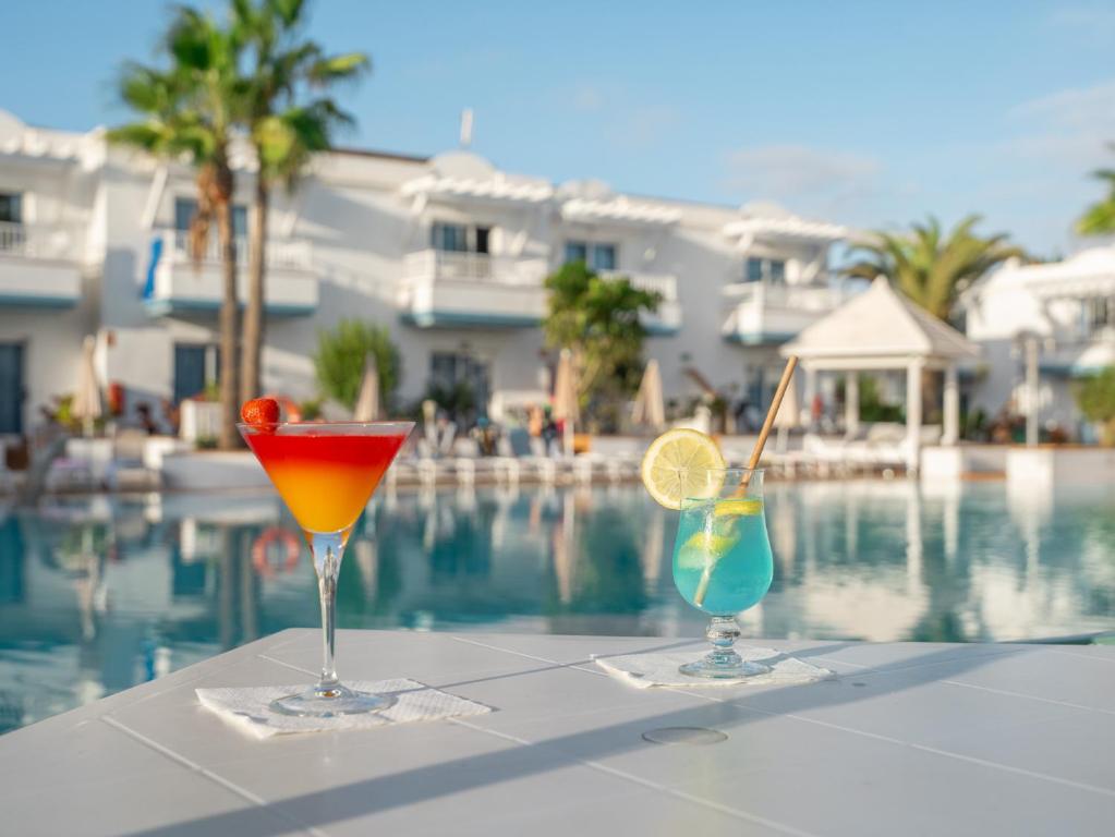 two cocktails sitting on a table next to a swimming pool at Arena Beach in Corralejo