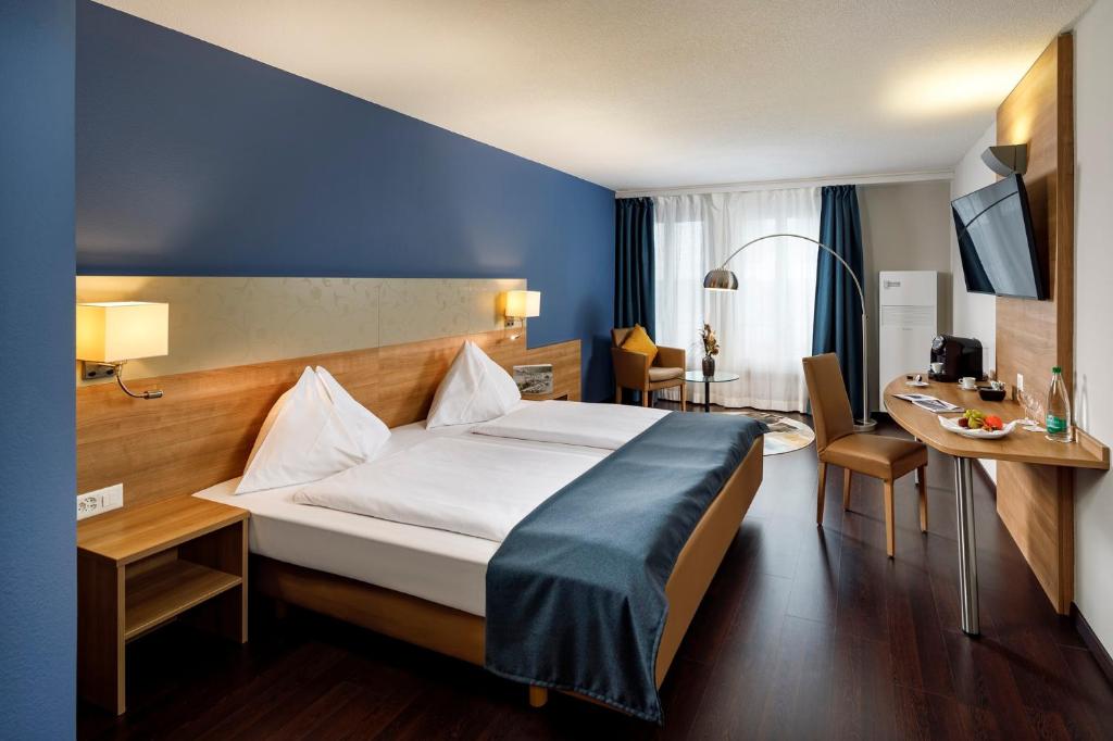 オルテンにあるホテル オルテン スイス クオリティのベッドとデスクが備わるホテルルームです。