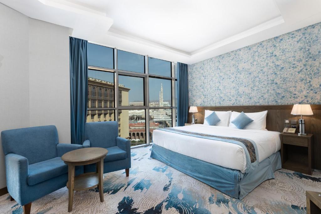 um quarto de hotel com uma cama e uma cadeira e uma janela em View Al Madinah Hotel em Medina
