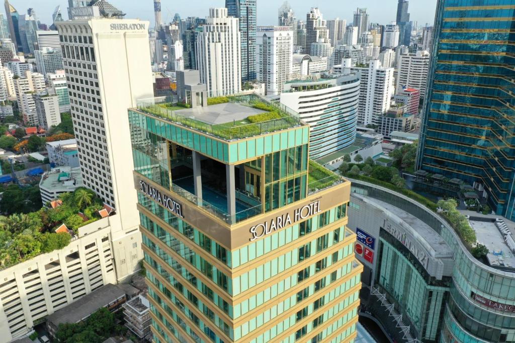 曼谷的住宿－曼谷索拉利亚西铁饭店，一座高大的建筑,有绿色屋顶,位于城市