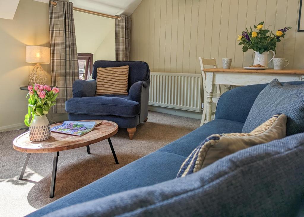 ein Wohnzimmer mit einem blauen Sofa und einem Tisch in der Unterkunft The Hayloft in Beadnell