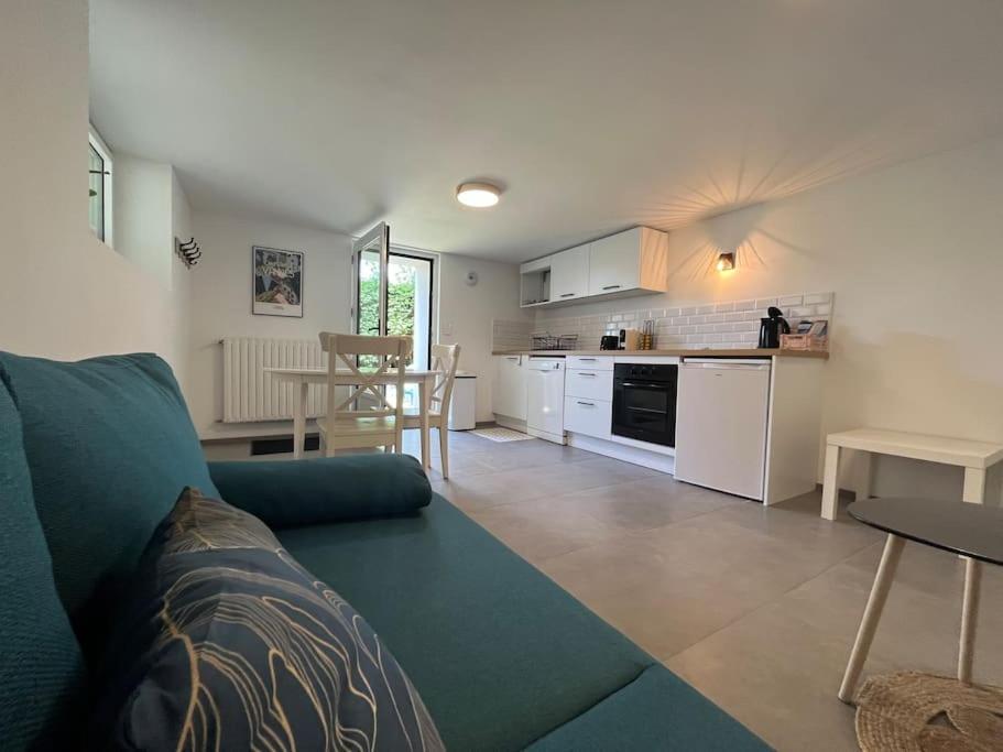 uma sala de estar com um sofá azul e uma cozinha em Appartement Vannes avec jardin em Saint-Avé