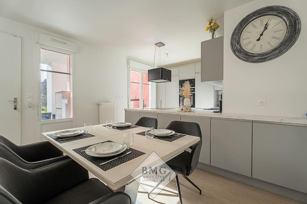 une cuisine avec une table à manger et une horloge murale dans l'établissement Scandinaves appartement Disneyland, à Serris