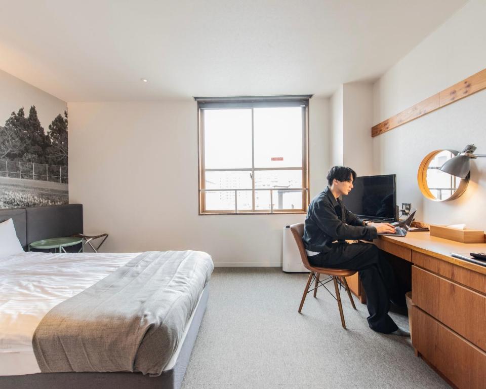 北九州市にあるホテルリリーフ小倉Annexのホテルの部屋の机に座っている男性