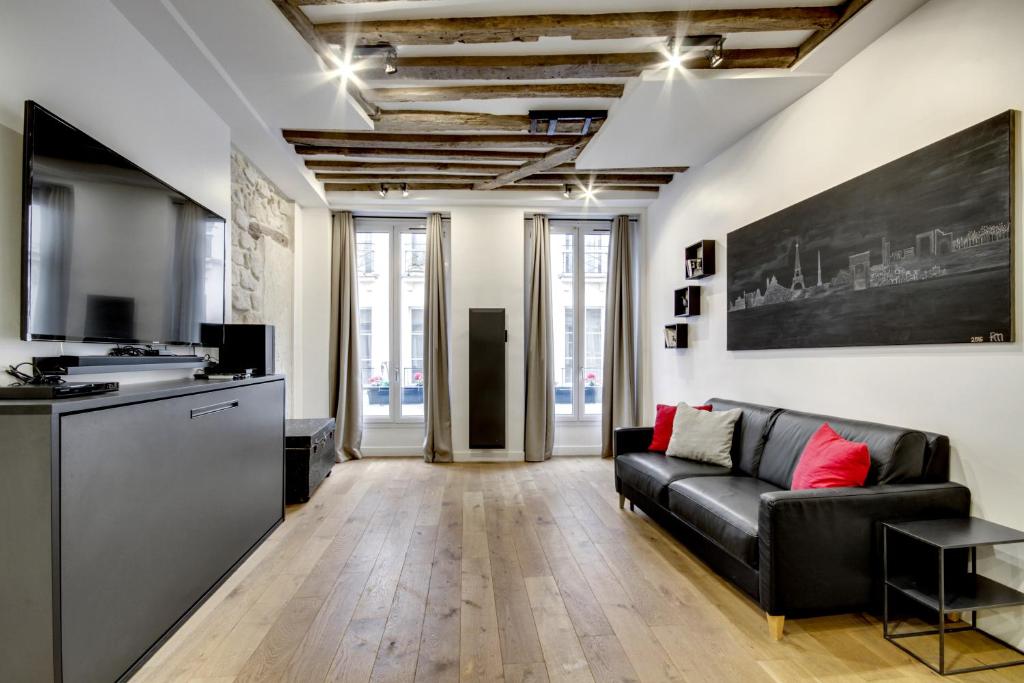 a living room with a black couch and a kitchen at mandar in Paris