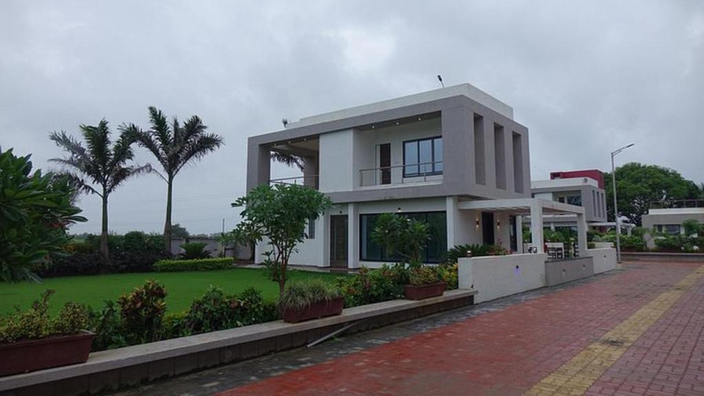 duży biały dom z drzewami i zielonym dziedzińcem w obiekcie Chandanvan Club & Resort w mieście Jalālpur