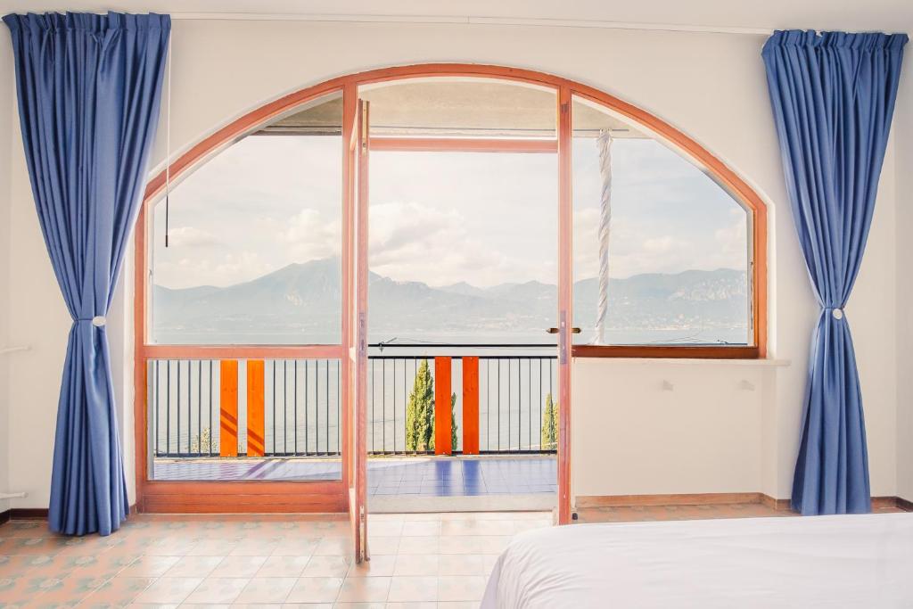 een slaapkamer met een groot raam met blauwe gordijnen bij Villa Mirella - Italian Homing in Torri del Benaco