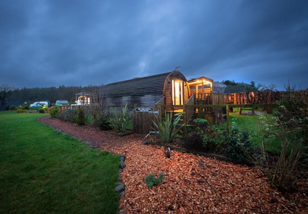 uma grande cabana de madeira num jardim à noite em Luxurious Family Pod with Garden and Hot tub - The Stag Hoose by Get Better Getaways em Glenluce