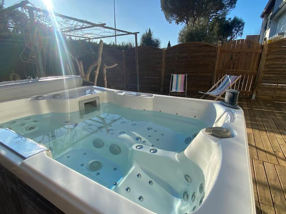 a jacuzzi tub in a backyard with the sun shining at La Contis spa in Saint-Julien-en-Born