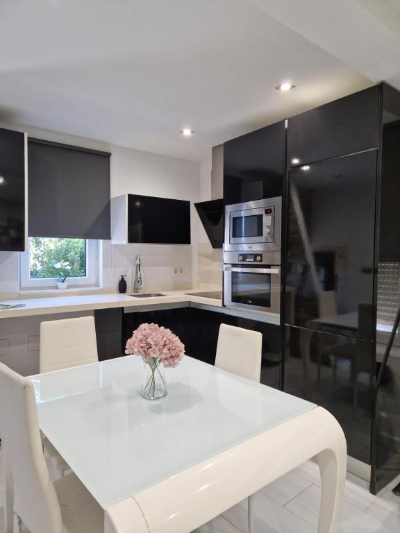 una cocina con una mesa blanca con un jarrón de flores. en La casita de Antonella - centro de Comillas, en Comillas