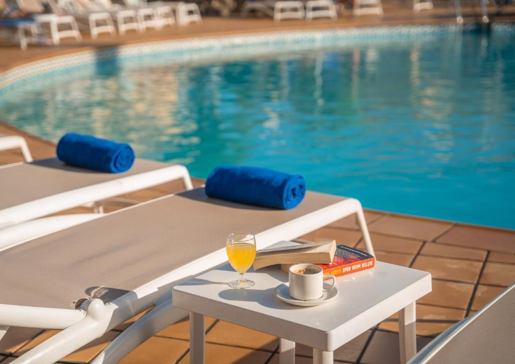 um copo de vinho numa mesa ao lado de uma piscina em Hotel Arena Suite em Corralejo