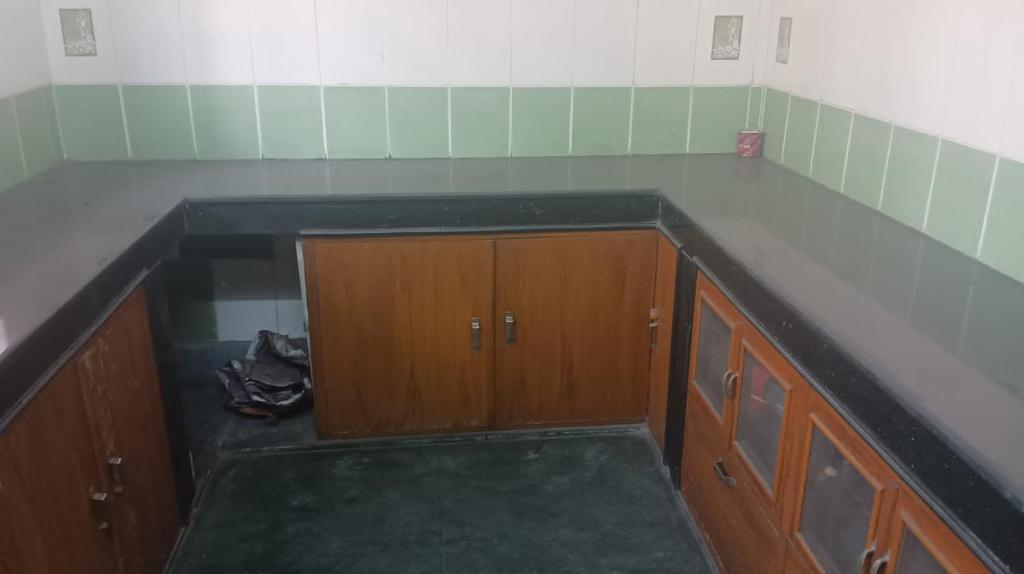 eine leere Küche mit Holzschränken und einer Arbeitsplatte in der Unterkunft Anjan Home Stay in Durgapur