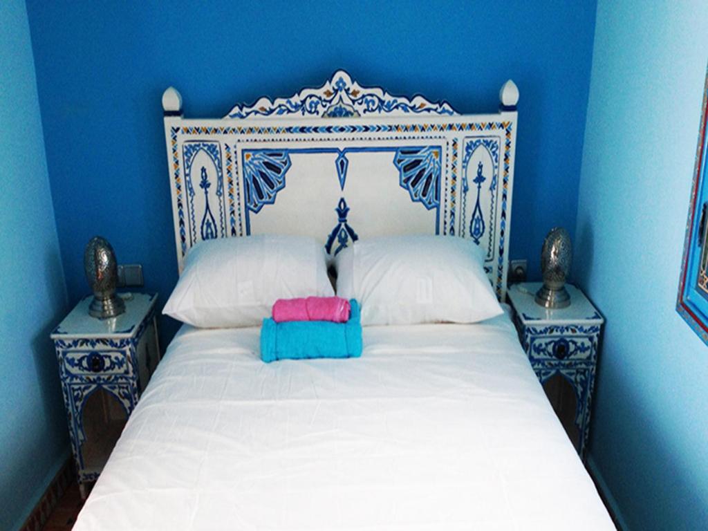 a blue bedroom with a white bed with two night stands at Dar Aldea in Chefchaouene