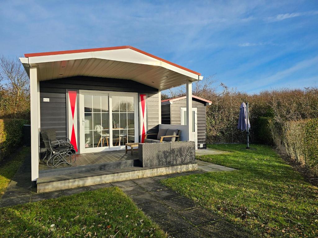 ein kleiner Schuppen mit einem Dach auf einem Hof in der Unterkunft Chalet Noelle SE14 in Serooskerke