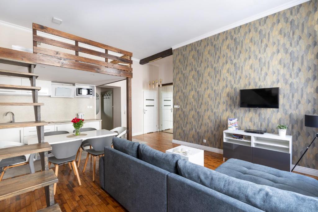 a living room with a blue couch and a tv at Fresh Apartments in Kraków