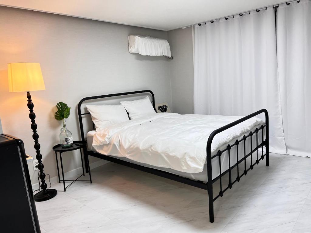 1 dormitorio con 1 cama con sábanas blancas y ventana en Terrace with Walking Trail Room 304 en Suncheon