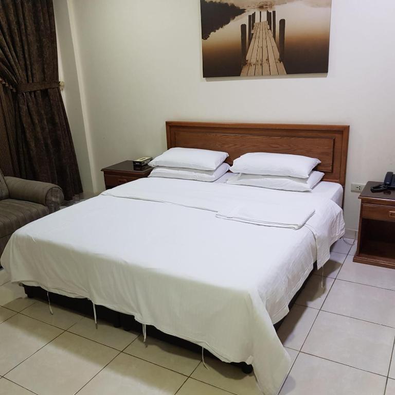 a bedroom with a large white bed and a couch at فندق زهرة الخليج in Dammam