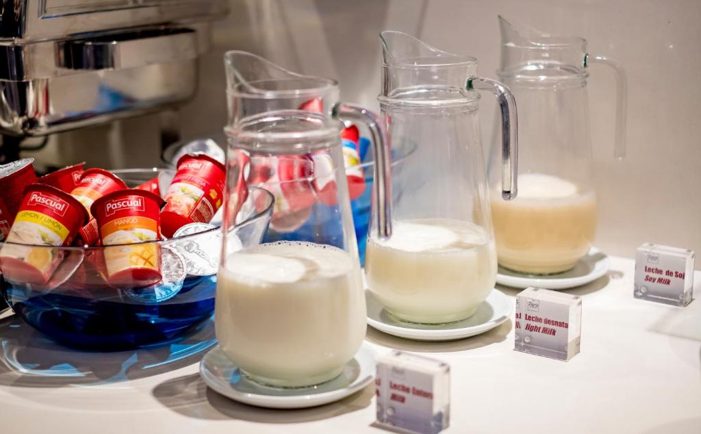 three containers of milk and a bowl of fruit at Zenit Valencia in Valencia