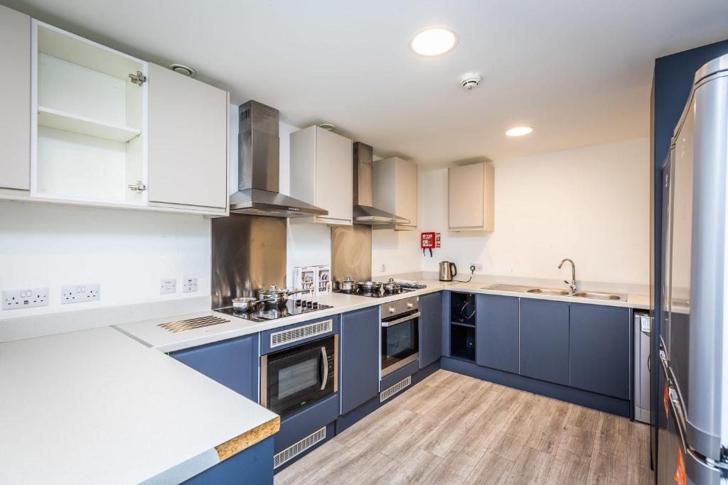 a kitchen with blue cabinets and white counters at Ensuite Room With Shared Kitchen, Close to Centre in Lincoln