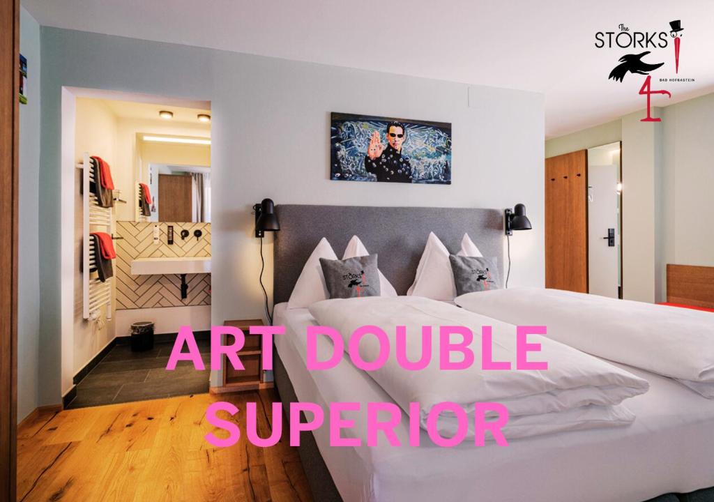 a bedroom with a large white bed and an art doubleauder at Hotel Bad Hofgastein - The STORKS - Adults Only in Bad Hofgastein