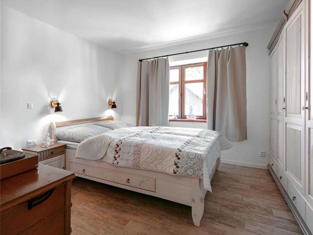 a white bedroom with a bed and a window at U líného jezevce in Abertamy