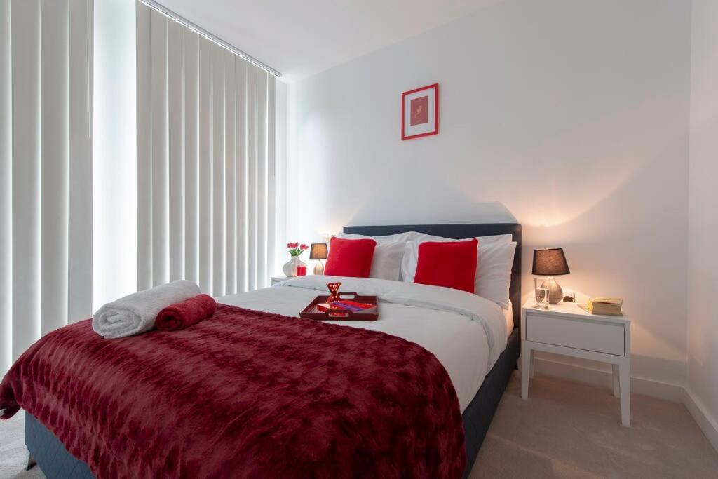 una camera da letto con un grande letto con cuscini rossi di Utopian Modern Apartments a Londra