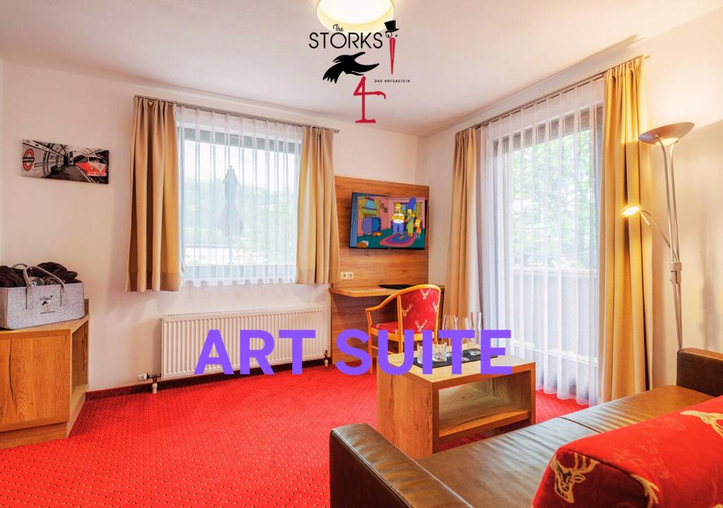 a living room with an art exhibit sign on the wall at Hotel Bad Hofgastein - The STORKS - Adults Only in Bad Hofgastein