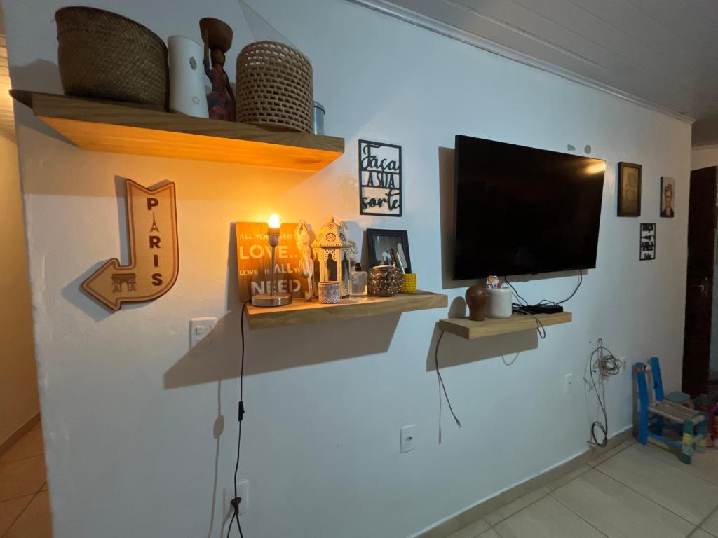 sala de estar con TV de pantalla plana en la pared en Legítima casa de praia en Capão da Canoa