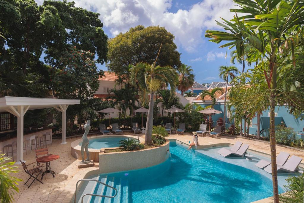 a pool at a resort with palm trees and chairs at Kura Botanica Hotel in Willemstad