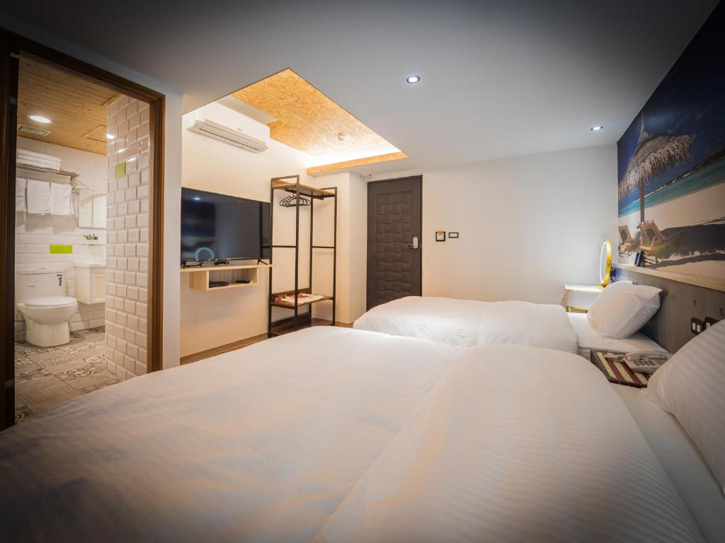 a hotel room with two beds and a bathroom at Good Time Boutique Hotel in Kaohsiung