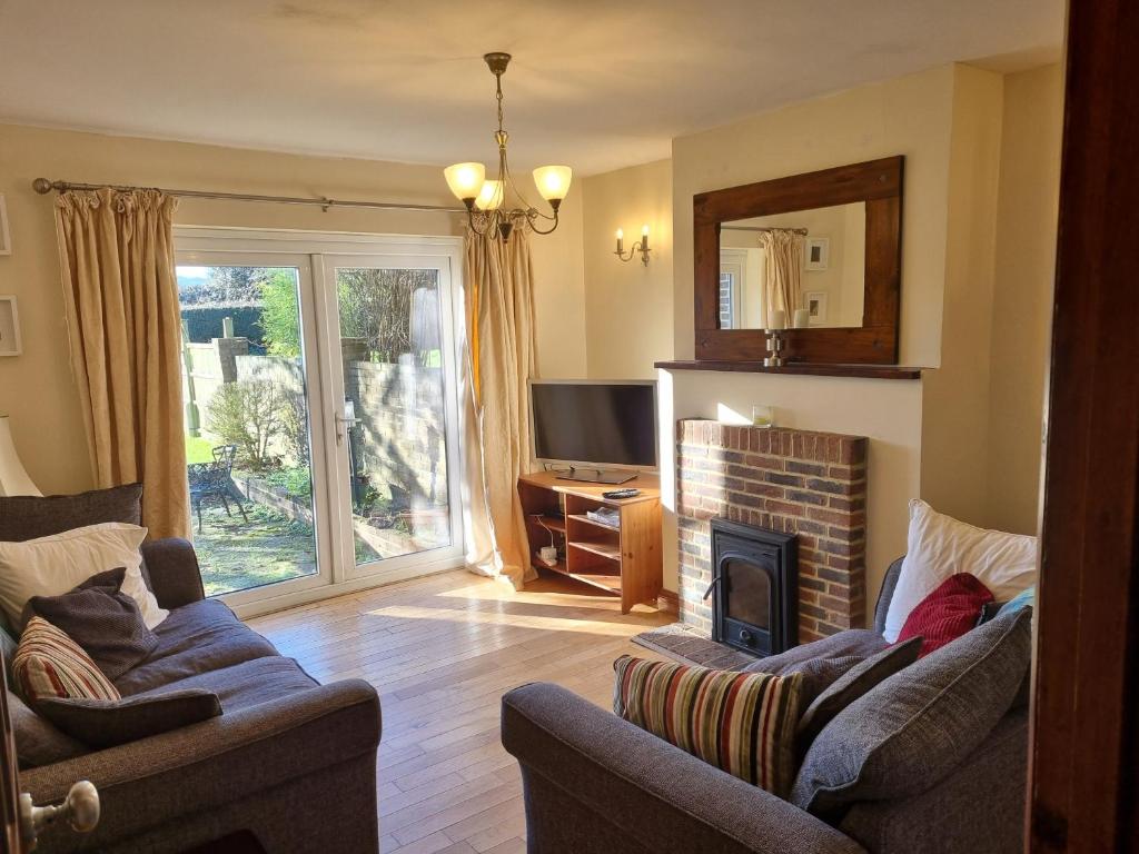 a living room with two couches and a fireplace at Maryland Cottage Nr Gatwick in Godstone