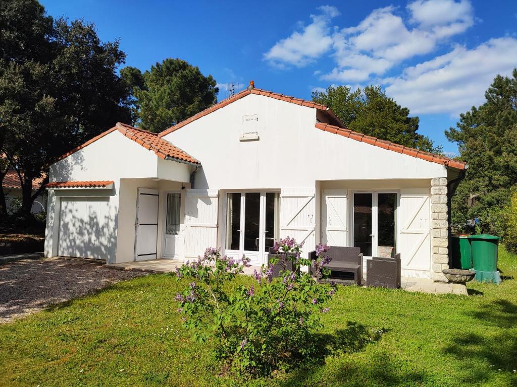 une petite maison blanche avec une pelouse dans l'établissement MAISON DE VACANCES, à Saint-Augustin