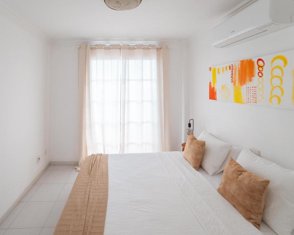a white bedroom with a large bed and a window at Villa Fariones in Tías
